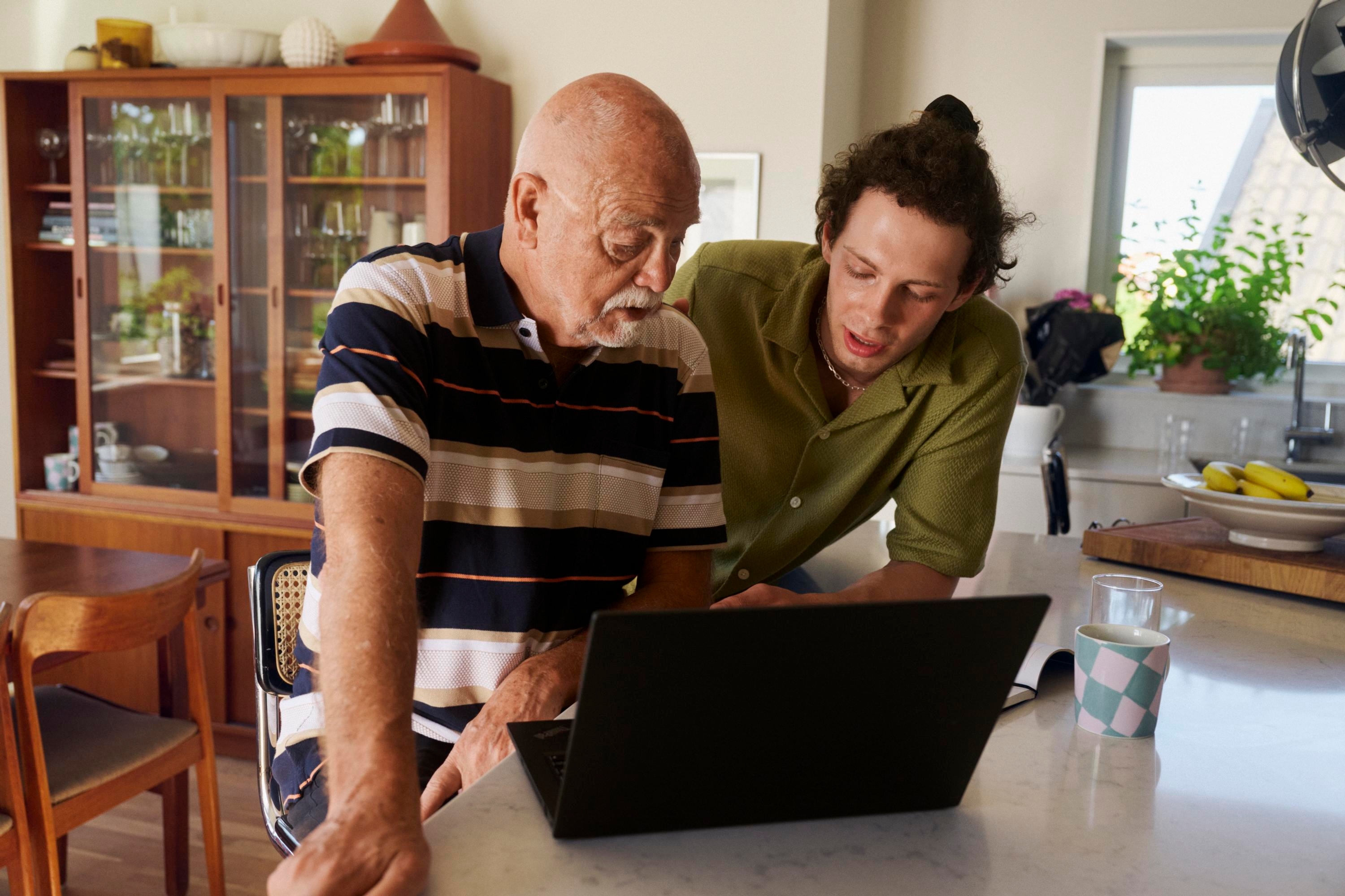 En ung man och en äldre man pratar framför en dator